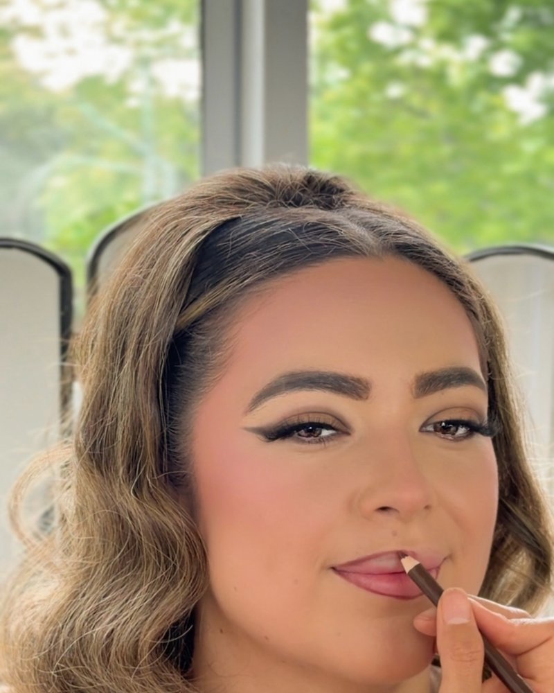 Thalia Castillo applying lip liner to a client